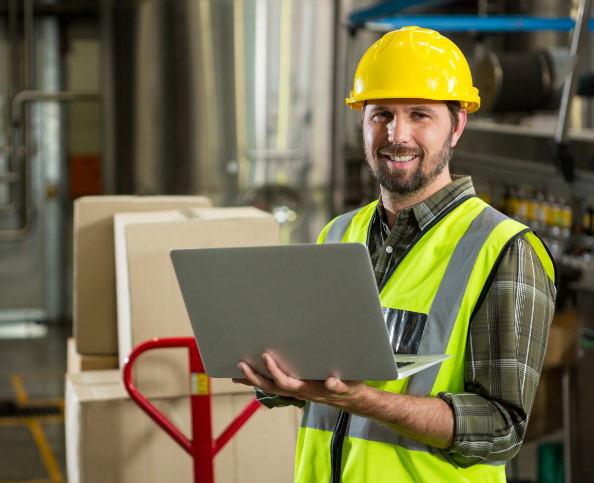 Portrait of smiling male worker using laptop in distribution warehouse