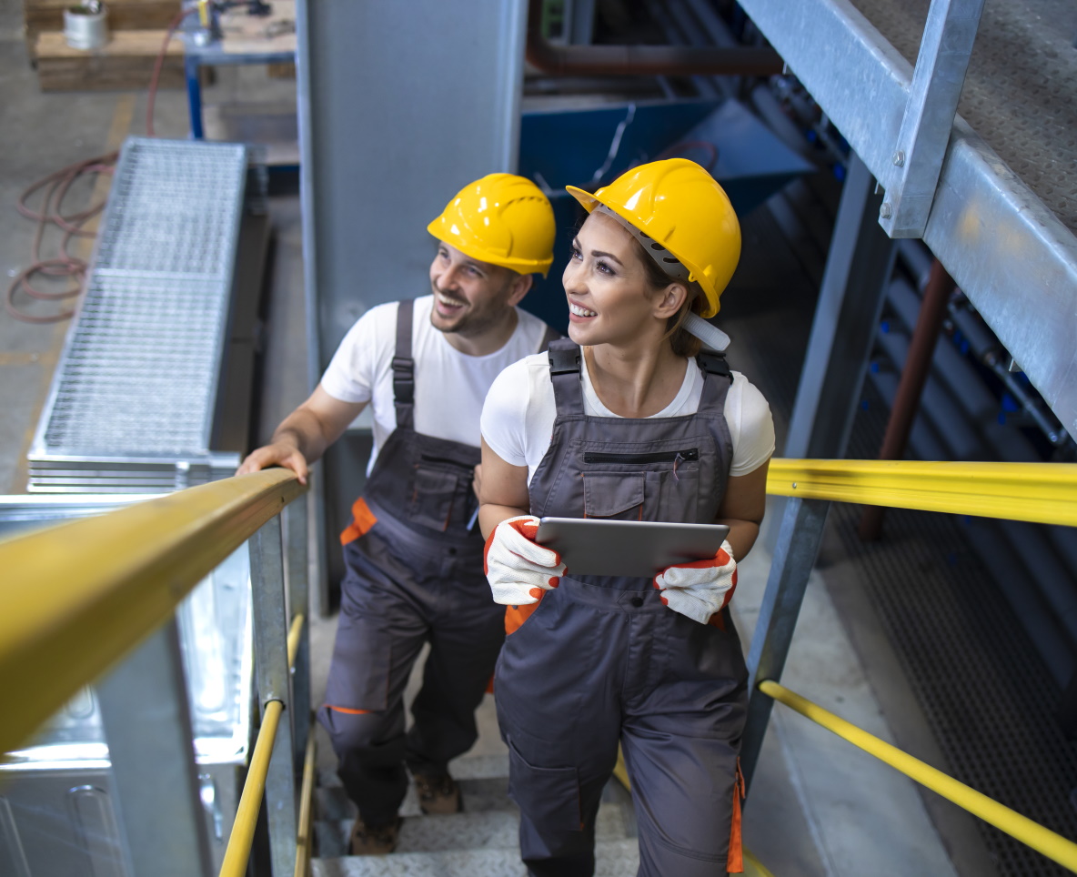 Industrial workers engineers walking in factory and climbing metal stairs.